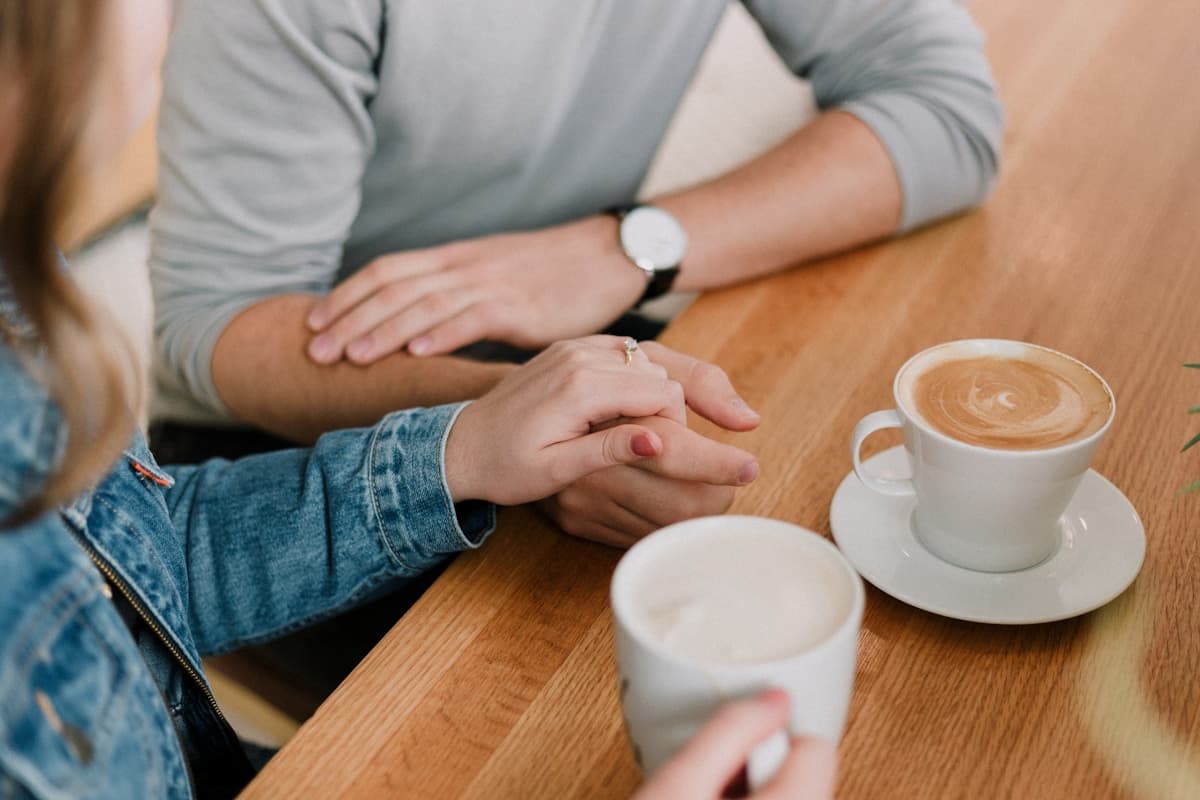 A couple holding hands over coffee at a warm cafe table