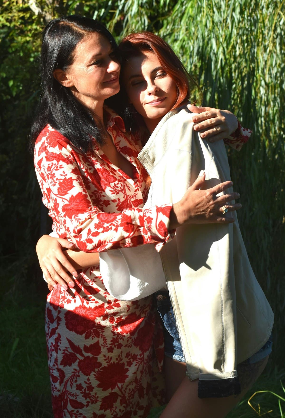 A mother and daughter embracing outdoors in sunlight